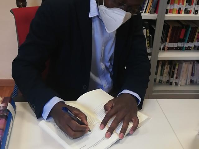 Patrick Kabou firma un ejemplar de 'Guerra y Paz en África' en la Mediateca Casa África